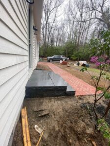 Slate steps and paved walkway leading to the house with construction area in the background.