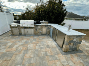 Outdoor kitchen with stone countertops and stainless steel appliances.