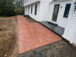 Paving stone walkway installation with a herringbone pattern leading to the entrance.
