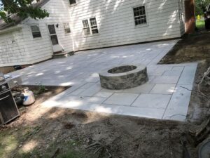 Backyard patio installation featuring stone fire pit centerpiece.