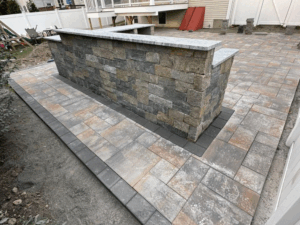 Backyard paving stonework with a stone wall and bar area installation.