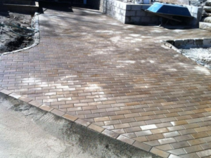 Brick paver driveway installation showing graded surface and aligned paving pattern